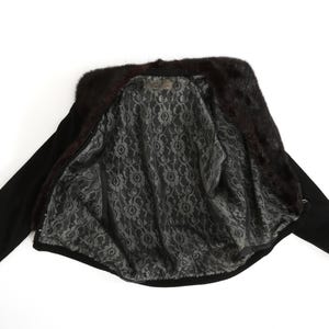 May include: A black fur-trimmed jacket with a black and white patterned lining. The jacket is unzipped and laid flat.