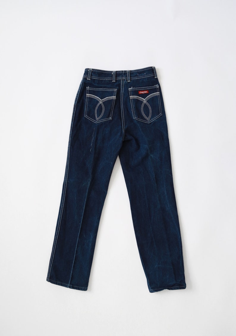May include: Dark blue denim jeans with white stitching detail and a red "CHARLIES" label on the back pocket.