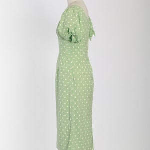 May include: A green dress with white polka dots and short puffed sleeves. The dress is fitted and has a scoop neckline.