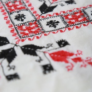 May include: White fabric with red and black embroidery in a geometric pattern.