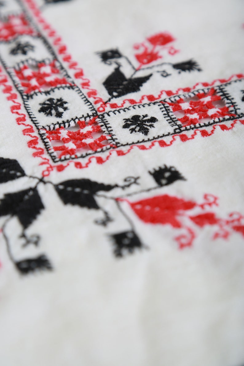 May include: White fabric with red and black embroidery in a geometric pattern.