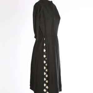 Puede incluir: Un vestido negro con una abertura lateral y un patr&oacute;n a cuadros blanco y negro debajo.