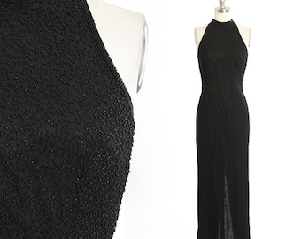 Könnte beinhalten: Ein schwarzes Halfterkleid mit einer perligen Textur. Das Kleid hat ein figurbetontes Oberteil und einen fließenden Rock.