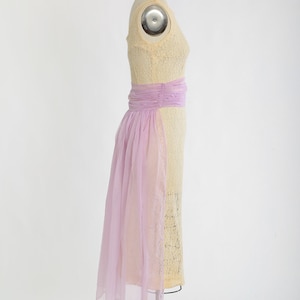 Op de afbeelding: Een vintage-stijl jurk met een cr&egrave;mekleurige kantboord en een lavendelkleurige chiffonrok. De jurk heeft een aansluitend lijfje en een zwierige rok.