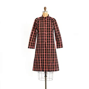 May include: A black and red plaid dress with a mandarin collar and button closure. The dress is on a mannequin.