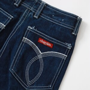 May include: Dark blue denim jeans with white stitching detail. The back pocket has a red label with the text "chardon paris" in white.