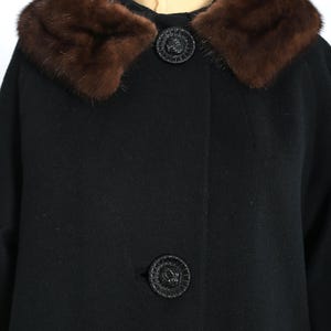 May include: A black coat with a brown fur collar and two decorative black buttons. The coat is made of a dark fabric and has a classic design, suitable for cold weather.