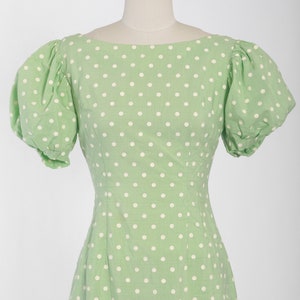 May include: A green dress with white polka dots and short puffed sleeves.