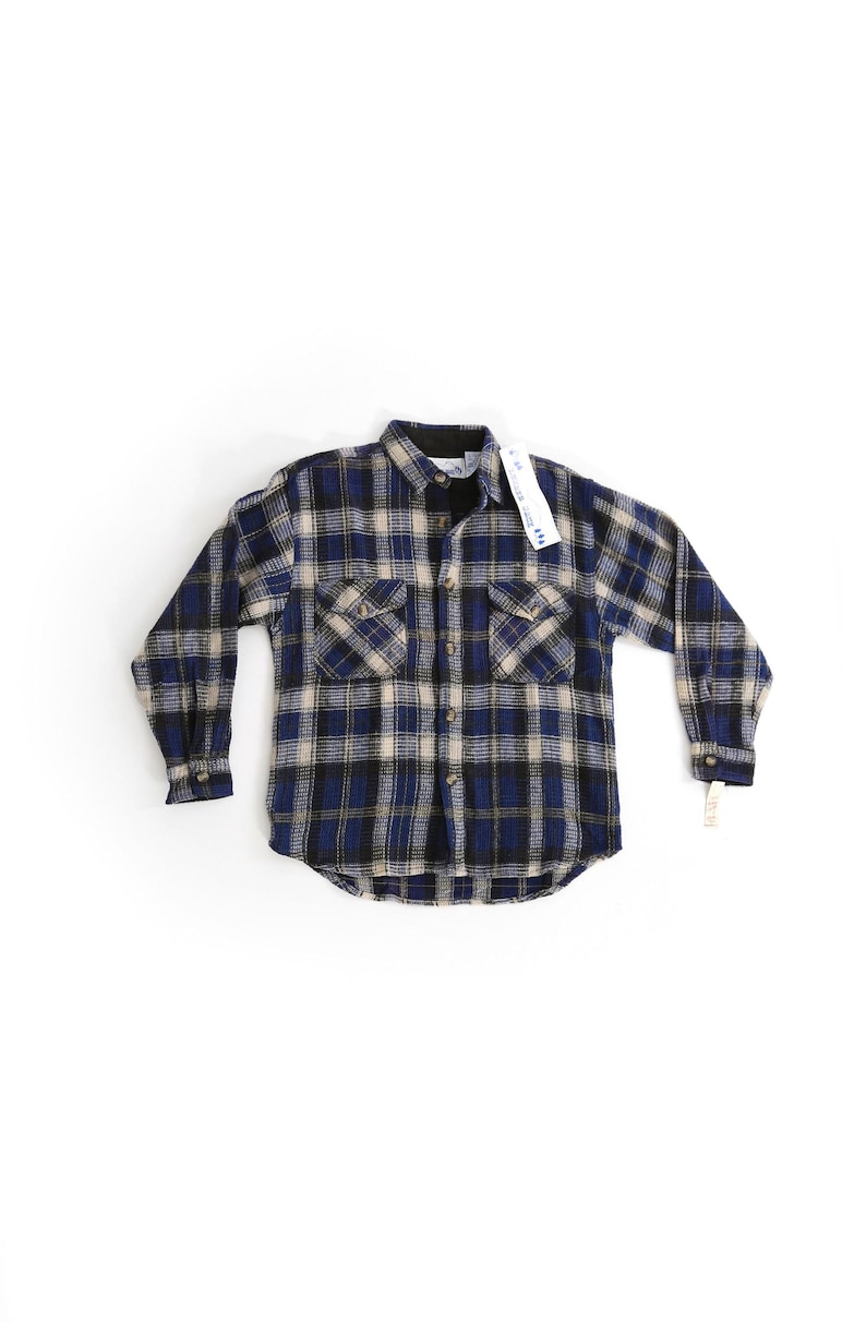 May include: A blue and beige plaid flannel shirt with long sleeves and two front pockets.
