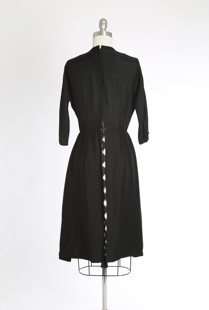 Puede incluir: Un vestido midi negro con una cremallera blanca y negra estampada en la espalda.