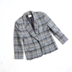 May include: A grey plaid blazer with blue and pink detailing. The blazer features a classic design with a notched collar, two front pockets, and a single-button fastening. The interior lining is a dark blue colour.