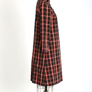 May include: A black and pink plaid dress with a mandarin collar and long sleeves. The dress is on a mannequin.