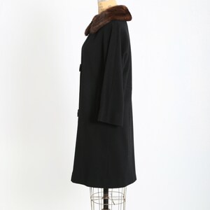 May include: A vintage black coat with a brown fur collar. The coat has a classic design with three buttons and three-quarter sleeves. The coat is displayed on a dress form.