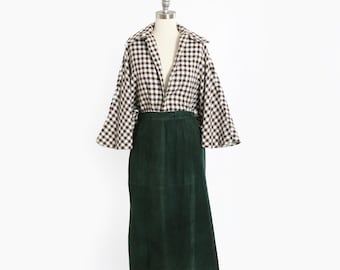 Könnte beinhalten: Ein Vintage-Outfit mit einem langen, dunkelgrünen Wildlederrock und einem braun-weiß karierten Oberteil mit weiten Ärmeln. Das Outfit wird auf einer Schaufensterpuppe vor weißem Hintergrund präsentiert und zeigt einen Retro-Stil.