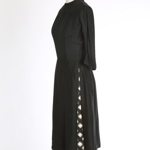 Puede incluir: Un vestido negro hasta la rodilla con un patr&oacute;n geom&eacute;trico blanco y negro en el lateral.