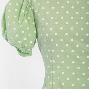 May include: A green dress with white polka dots and short puffed sleeves.