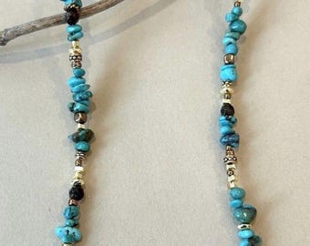 May include: A beaded necklace featuring irregular, tumbled turquoise-colored stones interspersed with small, metallic gold-toned spacer beads. The necklace includes a gold-toned lobster claw clasp and an adjustable chain link extender at the back.
