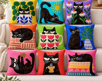 Pode incluir: Um conjunto de nove almofadas quadradas com ilustrações de gatos pretos. Cada almofada apresenta uma cena diferente, incluindo gatos com plantas, flores, canecas de café, novelos e padrões geométricos coloridos em amarelo, azul, roxo, laranja, verde, rosa e vermelho.