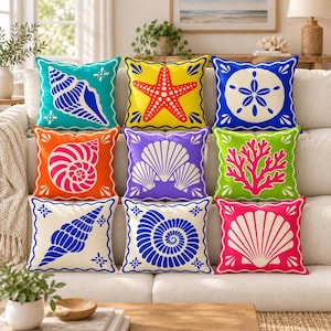 May include: A set of nine square throw pillows featuring vibrant colors and marine life illustrations, including a starfish, various seashells, a sand dollar, and coral, each with a decorative border and distinct, bold graphic patterns.