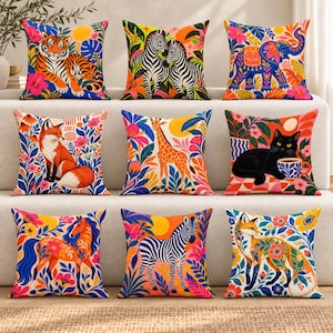 May include: A collection of nine square throw pillows featuring vibrant, colorful illustrations of animals including a tiger, zebras, an elephant, foxes, a giraffe, a black cat with a teacup, and a horse, all surrounded by lush floral patterns.