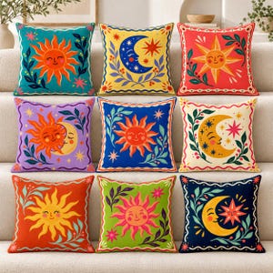 Puede incluir: Un conjunto de nueve cojines cuadrados con coloridas ilustraciones de soles, lunas y estrellas. Cada cojín muestra una combinación única de colores vibrantes que incluyen verde azulado, amarillo, rojo, morado, azul, crema, naranja y verde con detalles botánicos.