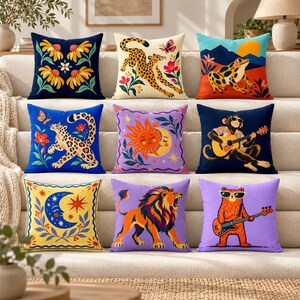 May include: A collection of nine square throw pillows featuring diverse graphic prints including a leopard, a frog, a monkey playing guitar, a sun and moon, a lion, and floral patterns in vibrant colors like blue, yellow, and purple.