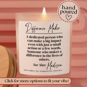 May include: A frosted glass candle with a wooden lid, featuring a white label that reads Difference Maker, a definition of the term, and the name Madison. The label also includes Q&M CandleCo, 8oz, Premium Soy Wax, and 35 hour burn text.