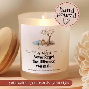 May include: A frosted glass candle in a jar with a wooden lid, featuring a label with a watercolor illustration of two characters walking near a tree. The text reads: Mrs. Wilson, Never forget the difference you make, Q&M Candle Co., 8oz, Premium Soy Wax, 35 hour burn.