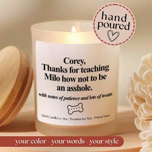 May include: A frosted glass candle in a jar with a wooden lid. The label reads: Corey, Thanks for teaching Milo how not to be an asshole. with notes of patience and lots of treats. It includes a bone icon, 8oz, and 35 hour burn text.