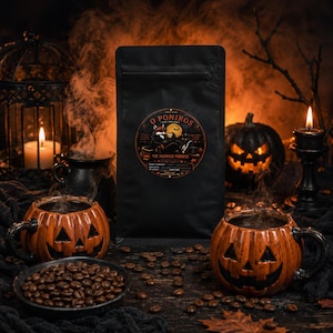 May include: A matte black coffee bag with a circular label featuring a fox illustration and the text O PONIROS THE HAUNTED PONIROS. The bag is surrounded by two orange jack-o'-lantern mugs, a small bowl of coffee beans, and scattered beans.