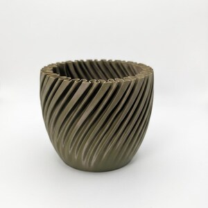 May include: A matte olive green planter with a rounded, bowl-like shape and a distinct exterior texture featuring diagonal, spiralling ridges that wrap around the entire circumference of the vessel, creating a consistent, repeating pattern.
