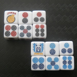 May include: White Mahjong tiles with red, blue, and black symbols. Some tiles have the word "JOKER" and a panda illustration. The tiles are arranged on a textured black surface.