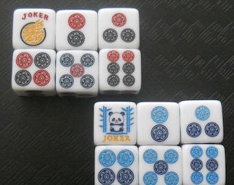May include: White Mahjong tiles featuring red, blue, and black symbols. Some tiles display the word "JOKER" and a panda illustration. The tiles are arranged on a textured black surface.