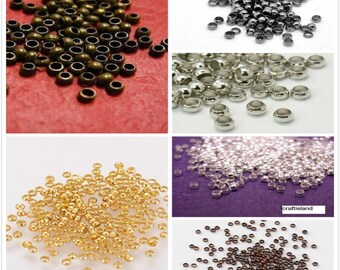 May include: Assortment of small metal beads in various colors, including gold, silver, bronze, and black. The beads are round with a small hole in the center.