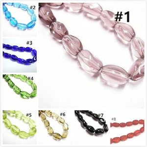 May include: Eight strands of glass beads in various colours and shapes. The beads are oval-shaped and have a glossy finish. The colours include light blue, dark blue, green, light green, brown, black, and red.
