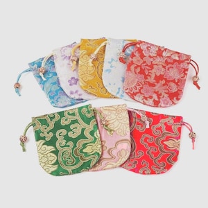 May include: A collection of small, colorful drawstring pouches. The pouches feature floral and ornate patterns in various colors, including red, green, yellow, and blue. Each pouch has a drawstring closure with decorative beads.