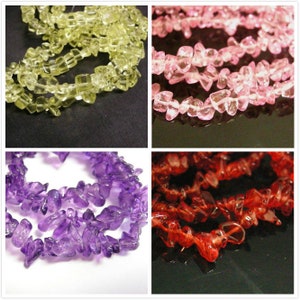 May include: Assortment of chip gemstone beads in various colours, including yellow, pink, purple, and red. The beads are irregular in shape and have a natural, rough texture.