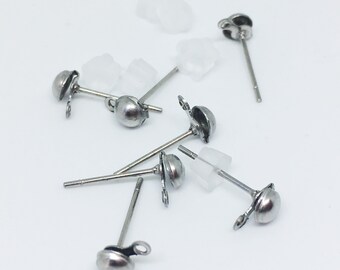 May include: A close-up of a group of silver earring posts with clear plastic stoppers. The earring posts have a small ball at the top and a loop for attaching earrings.
