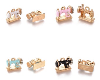 May include: Six gold-tone sewing machine charms with rhinestones. The charms are in different colors: white, pink, blue, black, and gold. The charms are perfect for adding a touch of whimsy to jewelry or crafts.