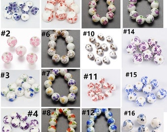 May include: Assortment of 16 ceramic beads with various floral patterns. The beads are white with different colored floral designs, including blue, purple, pink, red, and gold. Each bead has a hole in the center for stringing.