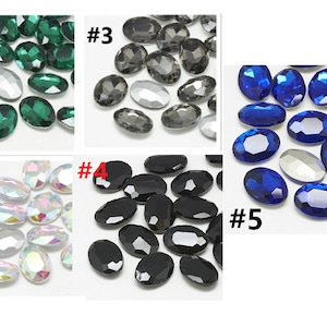 Op de afbeelding: Assortiment van ovale strasssteentjes in verschillende kleuren, waaronder groen, helder, grijs, zwart en blauw. De strasssteentjes zijn gerangschikt in vijf groepen, genummerd van #1 tot #5.