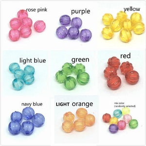 May include: Assortment of colorful plastic beads in various colors, including rose pink, purple, yellow, red, light blue, green, navy blue, light orange, and a mix of colors. The beads are all the same size and shape, and they have a textured surface.