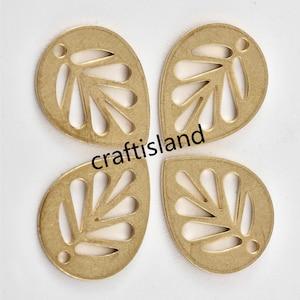 May include: Four gold-colored metal leaf-shaped charms with a cutout design. The charms have a hole at the top for attaching to jewelry or other crafts.