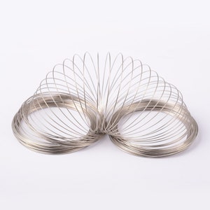 May include: A silver metal slinky toy, a classic spring toy that can be stretched and compressed.