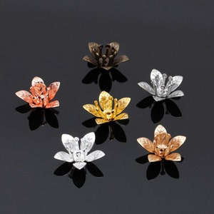 May include: Six flower-shaped metal bead caps in different colours: gold, silver, bronze, copper, and two shades of rose gold. The caps are designed with intricate details and are perfect for adding a touch of elegance to jewellery projects.