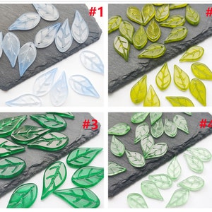 May include: Four sets of glass leaf shaped beads. The first set is light blue, the second is yellow-green, the third is dark green, and the fourth is light green.