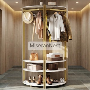 May include: A gold metal rotating coat rack with white marble-look shelves, featuring the text MiseranNest. The unit holds a white hat, beige scarf, umbrella, white shirt, brown jacket, yellow resistance band, handbag, storage boxes, and boots.
