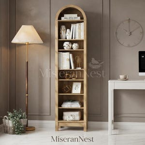 May include: A tall, arched wooden bookcase with seven shelves, filled with books, decorative vases, and geometric sculptures. The unit features a light wood finish and a curved top design, providing organized storage for various home decor items.