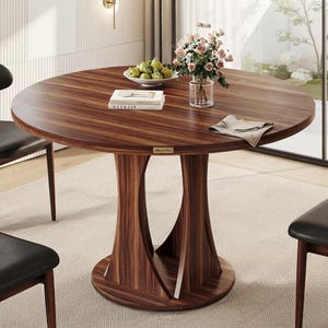 May include: A round dining table with a dark brown wood grain finish, featuring a central pedestal base with curved supports. On the tabletop sits a white bowl of green pears, a glass vase with pink roses, a book, and a folded beige napkin.