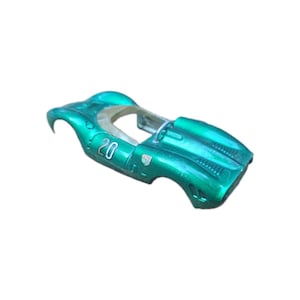 May include: A metallic green model race car body shell featuring the number 20 printed in white on the side. The exterior includes a small checkered flag emblem near the front wheel arch, a curved windscreen frame, and moulded air intake vents on the bonnet.